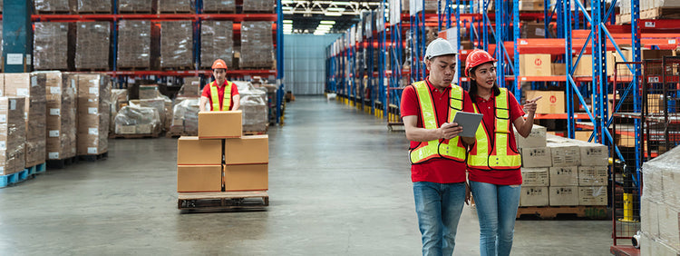 Two workers in a warehouse with shelves and boxes.